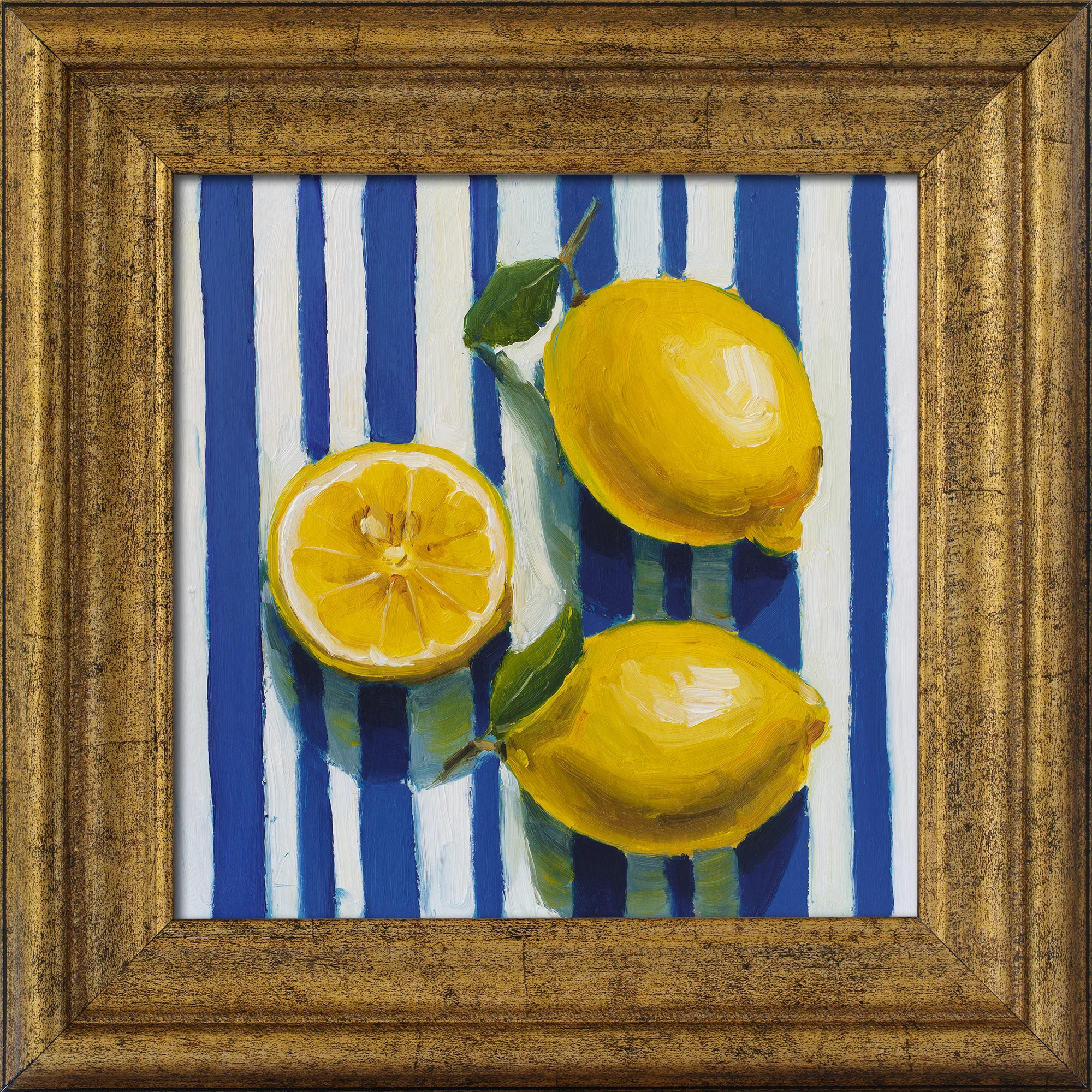 An oil painting in a textured gold frame depicting bright yellow lemons—two whole with green leaves and one sliced open—resting on a light blue and white vertical striped cloth.